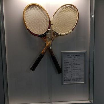 vanhoja tennismailoja esillä vitriinissä
